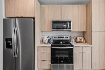 a kitchen with stainless steel appliances and wooden cabinets at Altis Grand Suncoast, Florida