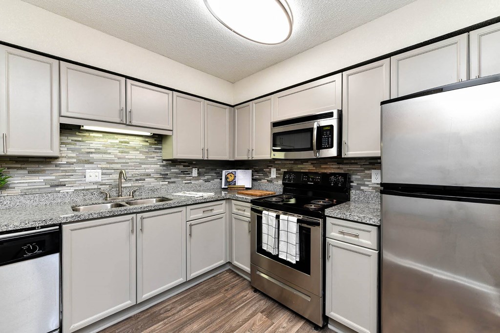 a kitchen with white cabinets and stainless steel appliances  at District at Vinings, Georgia