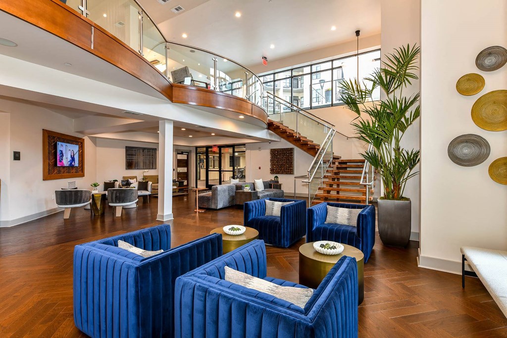 a large room with blue chairs and a staircase in the background