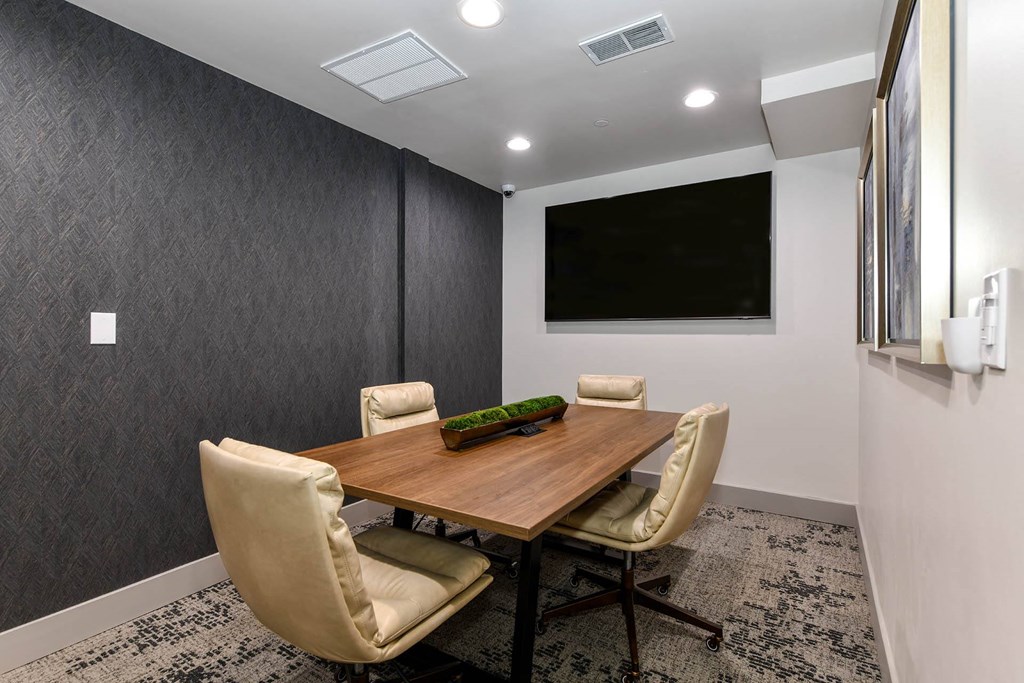 a conference room with a table and chairs and a tv on the wall