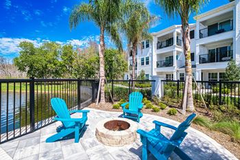 a patio with blue chairs and a fire pit in front of an apartment building  at Altis Grand Suncoast Apartments, Florida, 34638