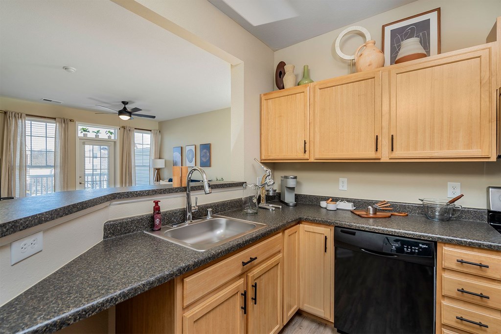 A kitchen with wooden cabinets and a black dishwasher.