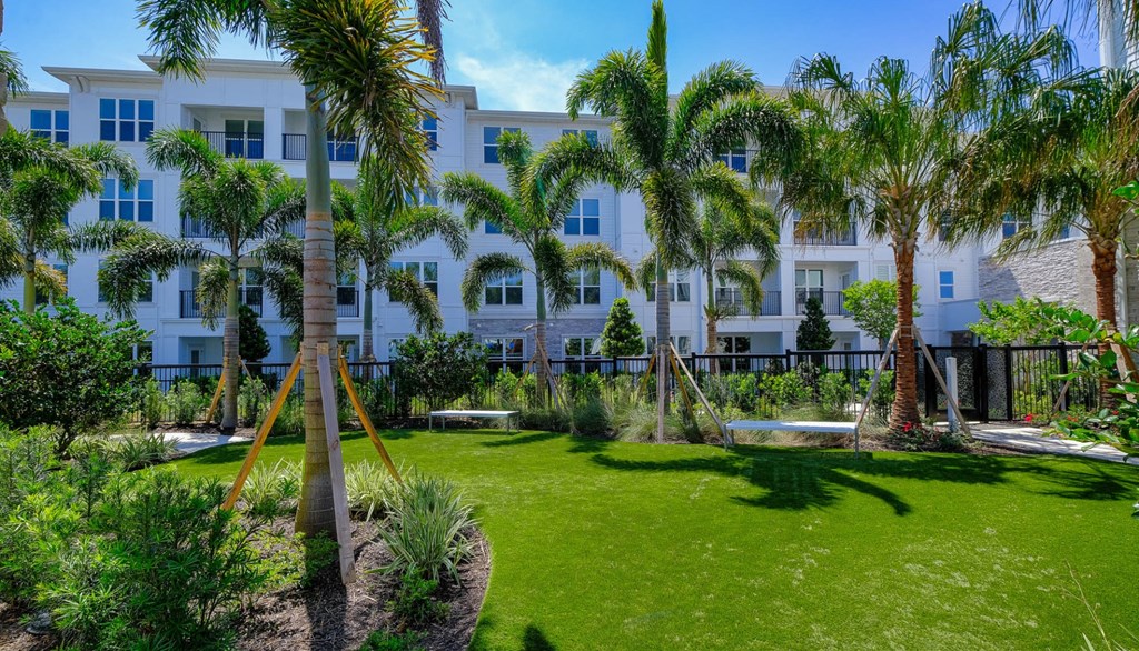 a yard with palm trees in front of a white building