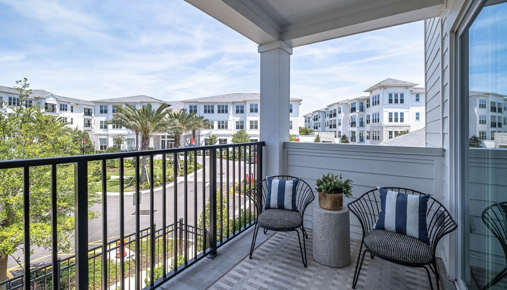 a balcony with two chairs and a view of a building and a beach