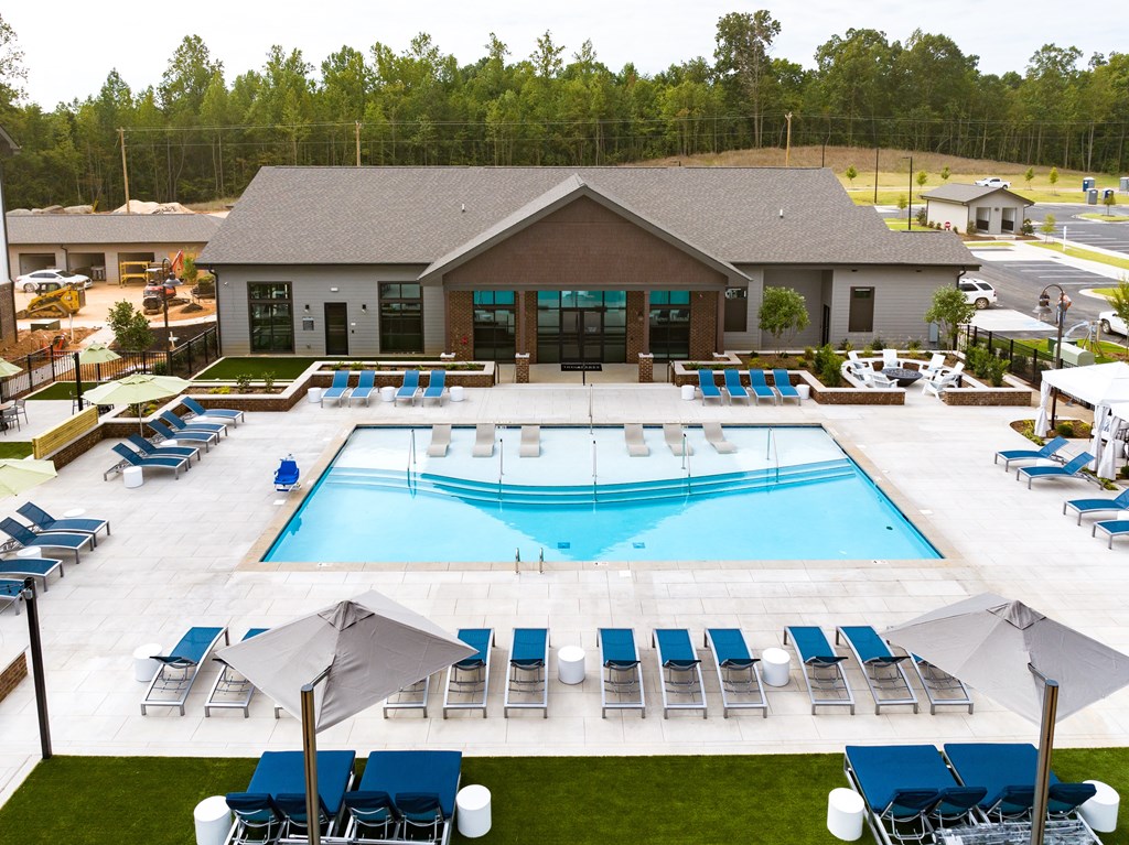 an aerial view of a pool with lounge chairs and a building