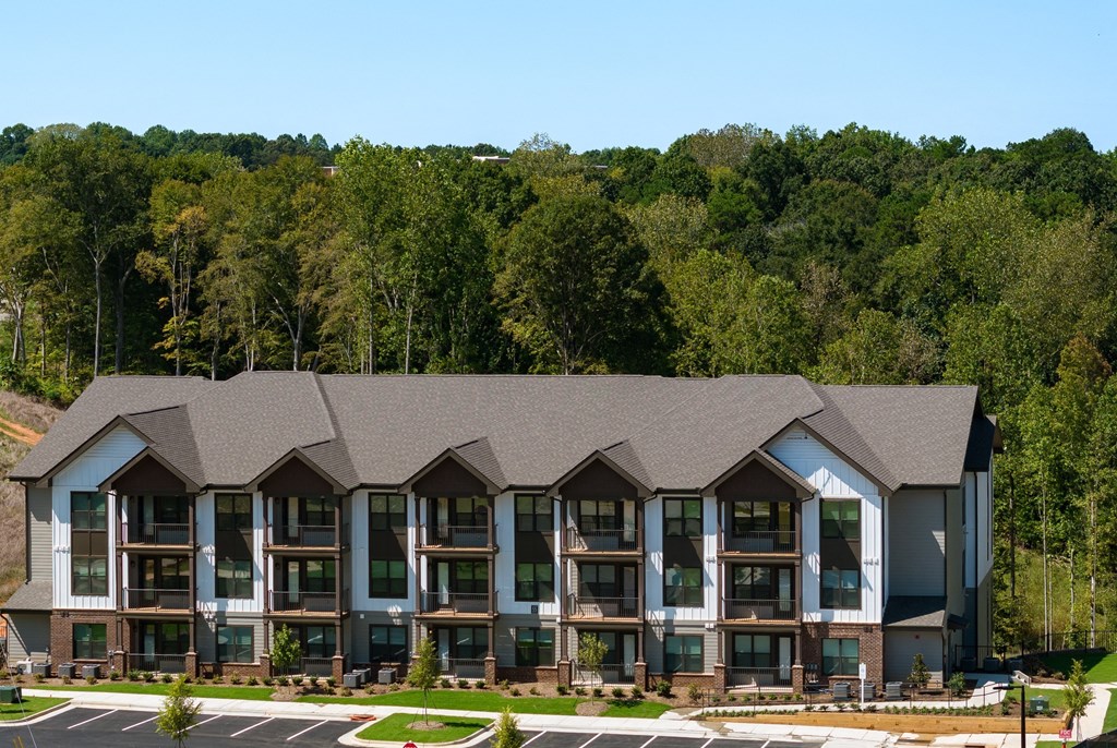 an aerial view of an apartment building with a forest in the background