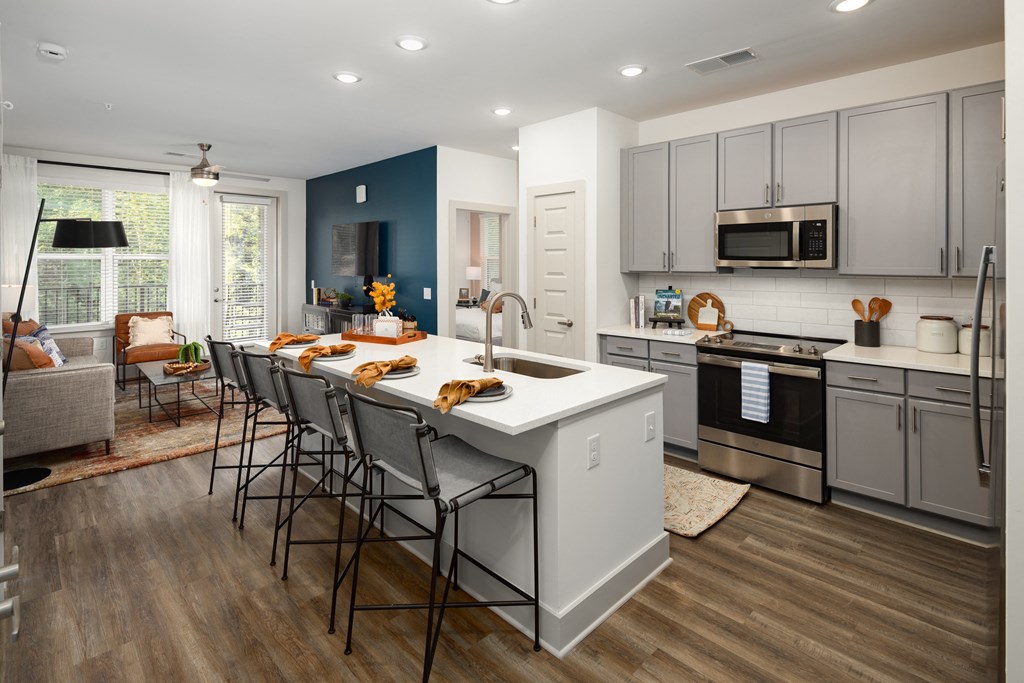 Apartments for Rent in Belmont, NC - Banks at Mt. Holly - Open-Concept Kitchen with Wood-Inspired Plank Flooring, Island/Breakfast Bar with Seating, Stainless-Steel Appliances, Quartz Countertops, Subway Tile Backsplash, Grey Cabinets, and Access to Living Area