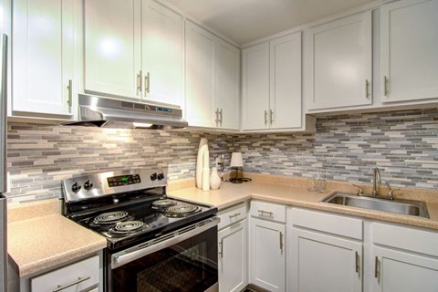 a kitchen with white cabinets and a stove and a sink