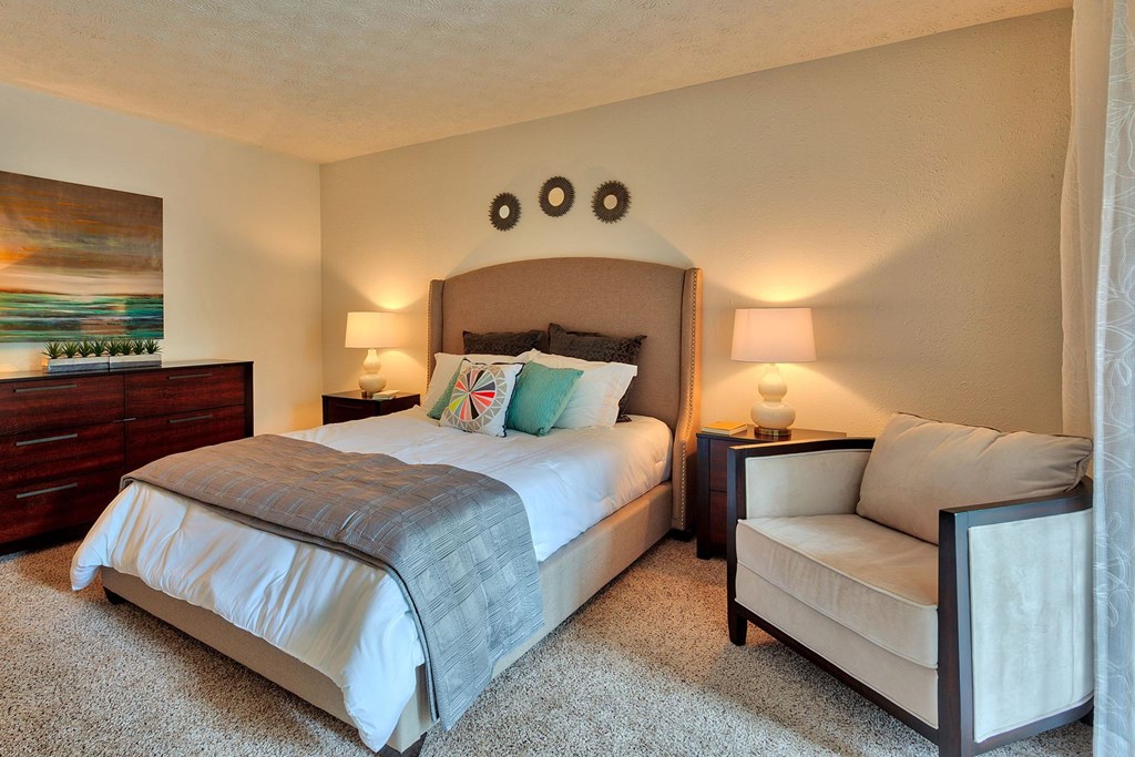 A bedroom with a large bed and a smaller bed with a white chair beside it.