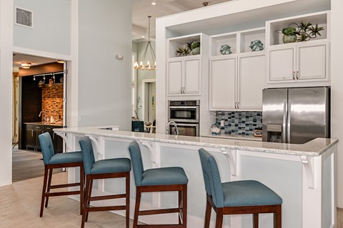 A kitchen with white cabinets and a bar area with blue chairs.