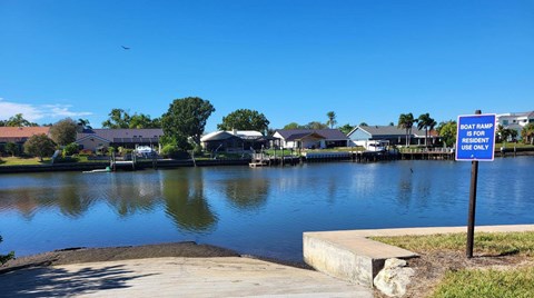 A blue sign on a post by the water reads "Boat Ramp is for Residents Only.".