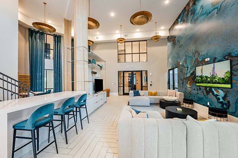 A modern living room with a bar area and a large painting on the wall.