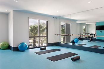 A gym with exercise equipment and a mirror on the wall.