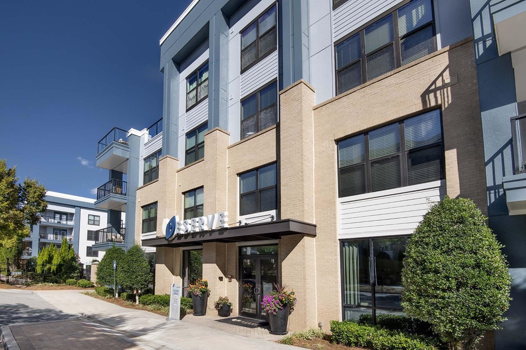 A modern building with a balcony and a small garden in front.