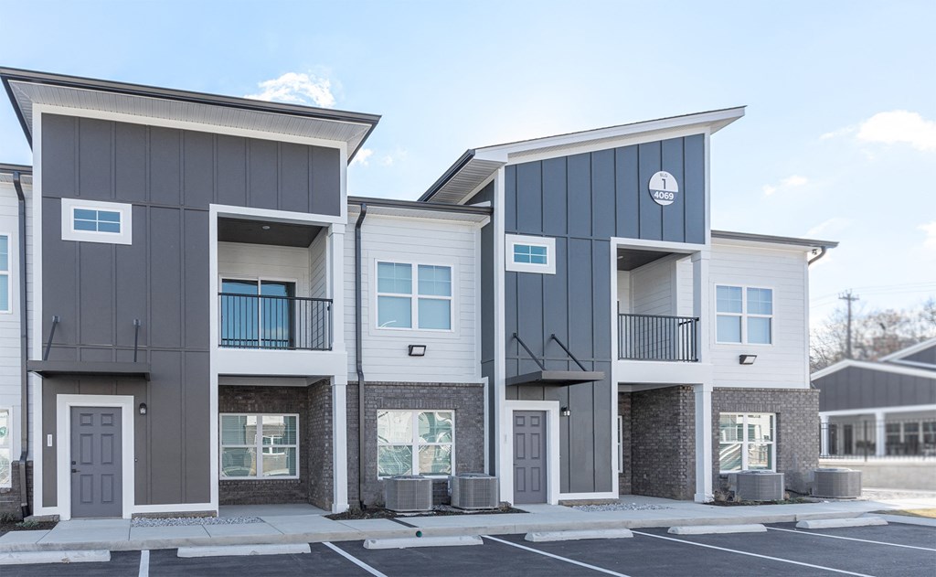 a street view of three apartment buildings with a parking lot