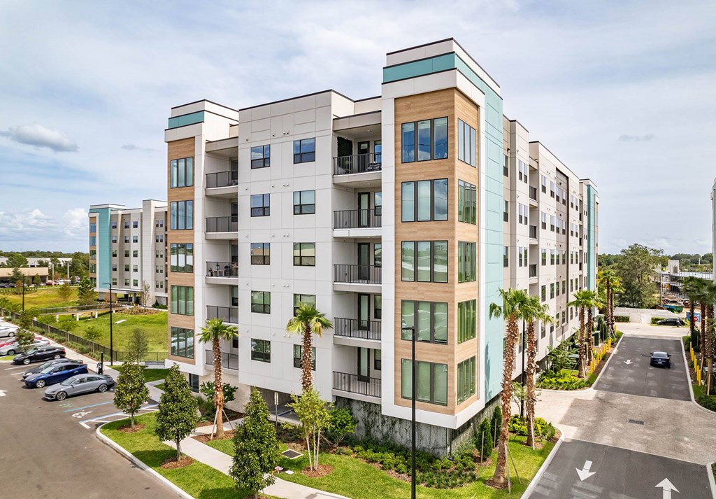 a building with palm trees in front of it near a parking lot