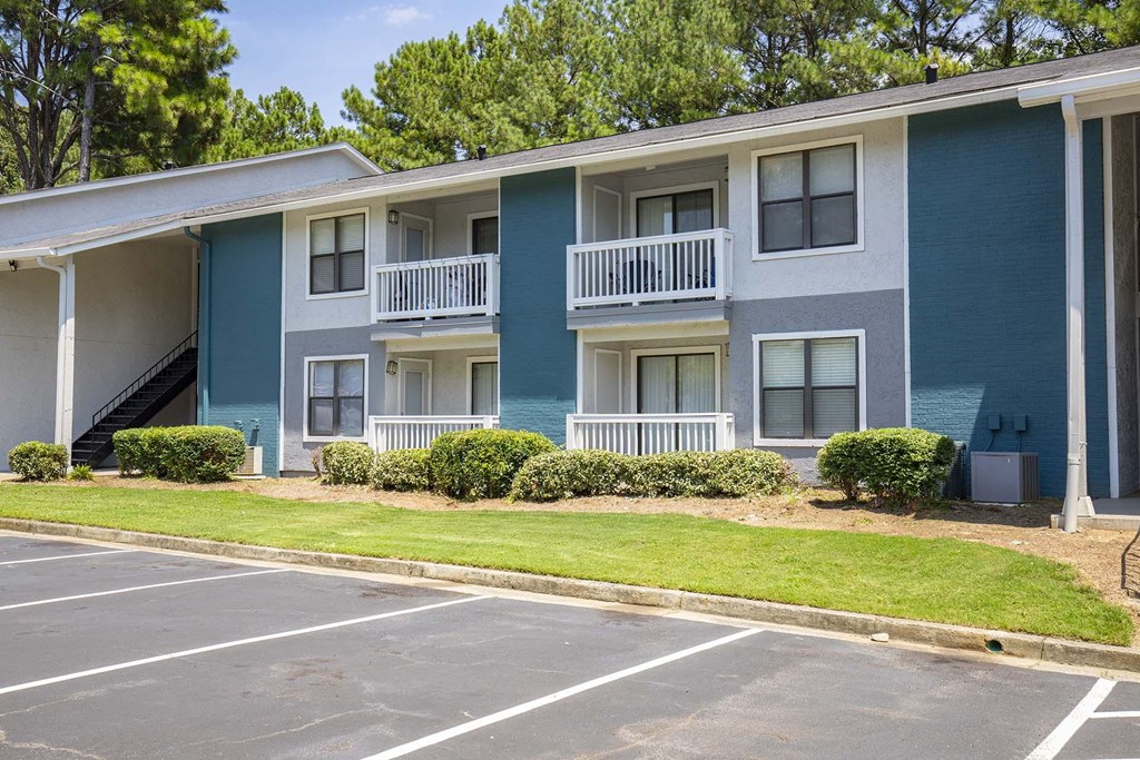 A blue and white apartment building with a parking lot in front.