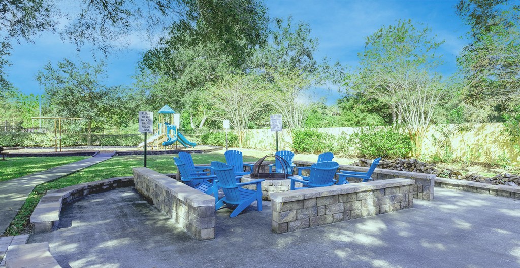 a seating area with blue chairs and a playground in a park