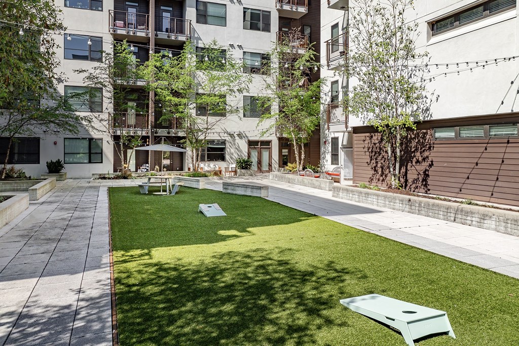 A green lawn in front of a building with a white bench.