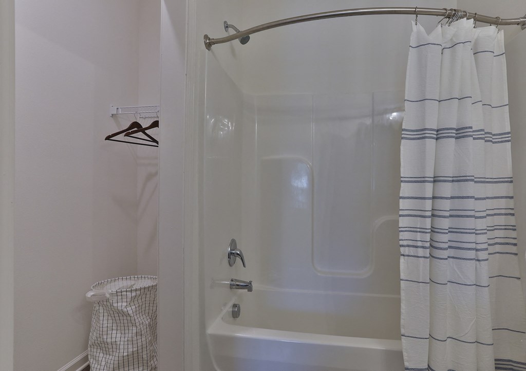 A white bathroom with a shower curtain and a white tub.