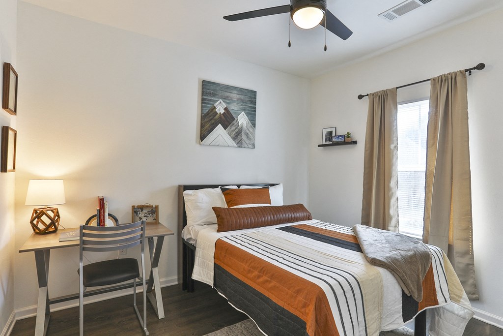 A bedroom with a bed, desk, and chair.