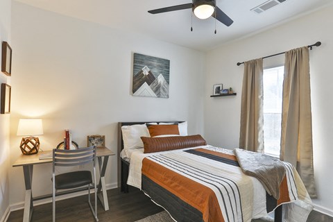 A bedroom with a bed, desk, and chair.