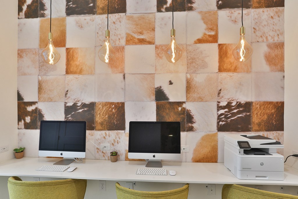 Two computer monitors on a desk with a wallpapered background.