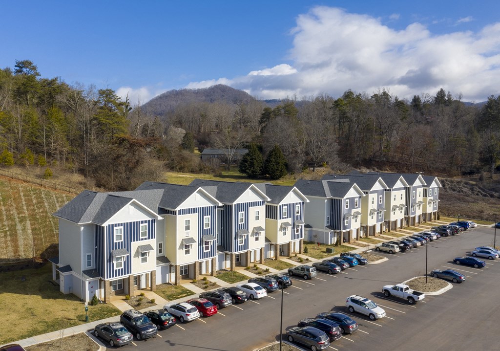 A row of houses with cars parked in front.
