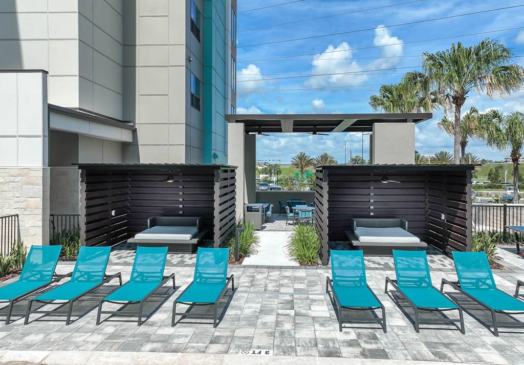 a lounge area with blue chairs and umbrellas and a building in the background