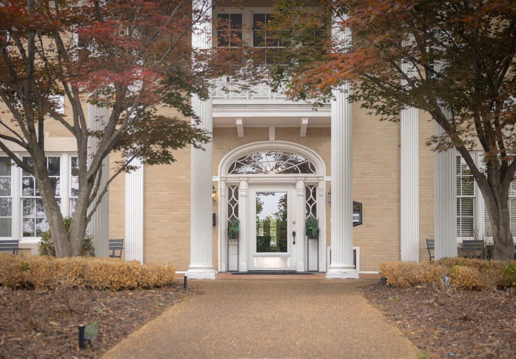 a white door on a brick building with trees in front of it