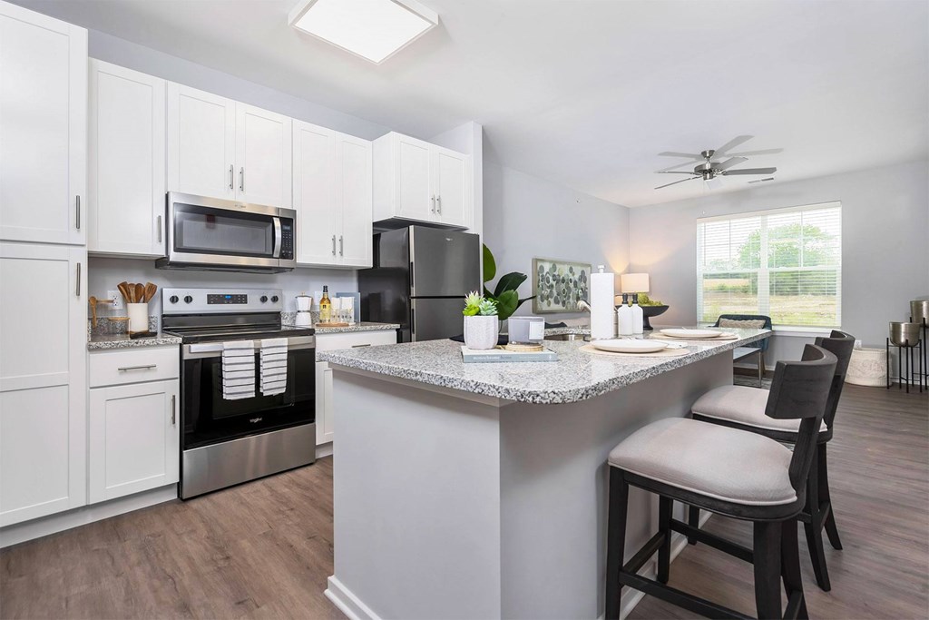 A kitchen with a white island and a black refrigerator.
