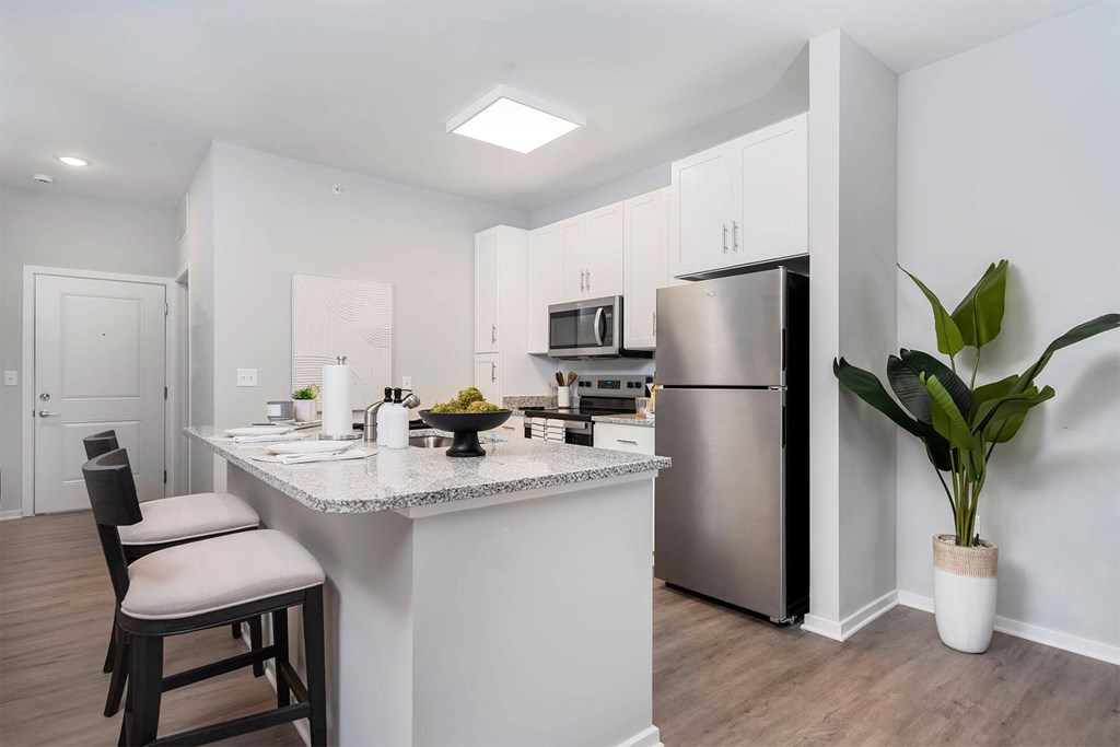 A kitchen with a stainless steel refrigerator, microwave, and wooden floors.