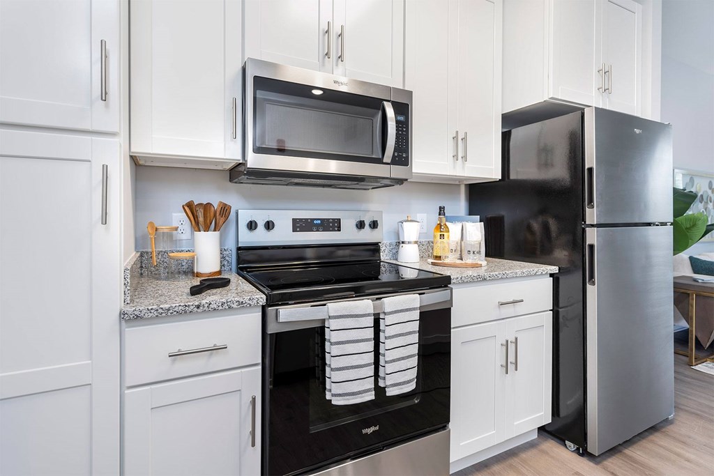 A modern kitchen with white cabinets and stainless steel appliances.