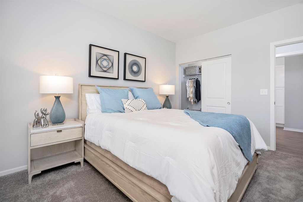 A bedroom with a bed, nightstand, and two wall art pieces.