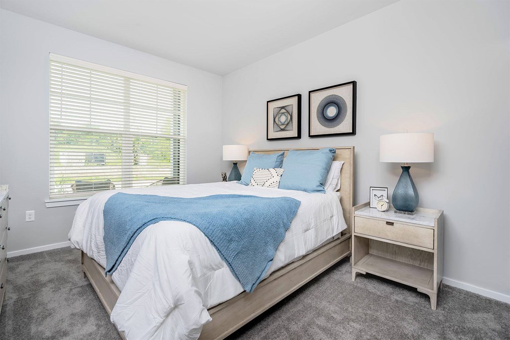 A bedroom with a bed, nightstand, and two wall art pieces.