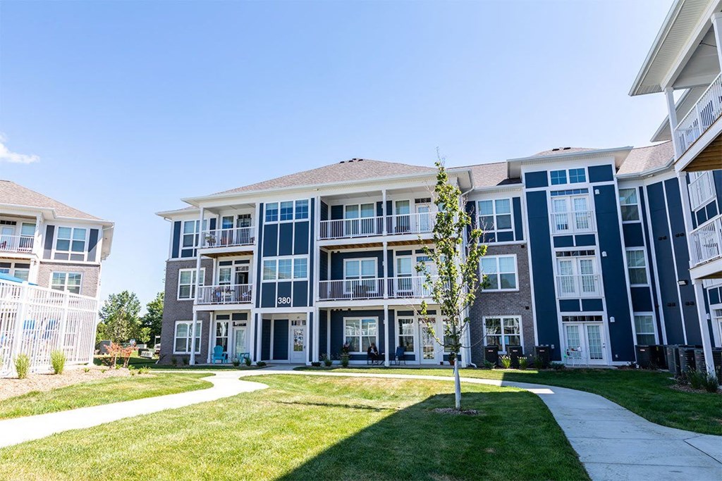 A tree stands in front of apartment buildings.