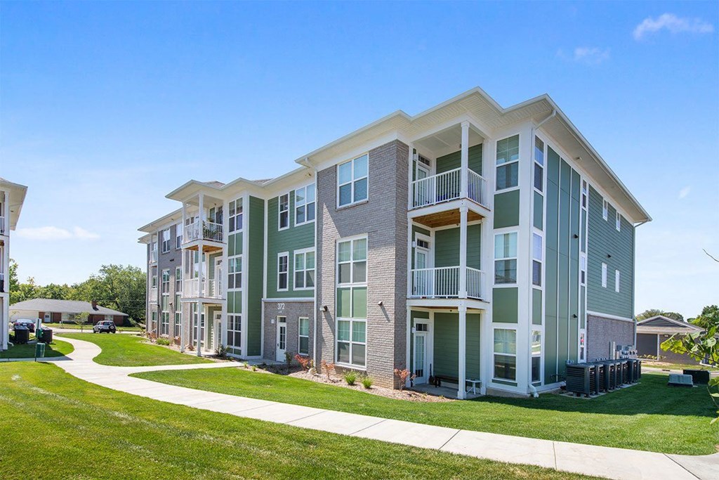 A modern apartment building with a well-maintained lawn in front.