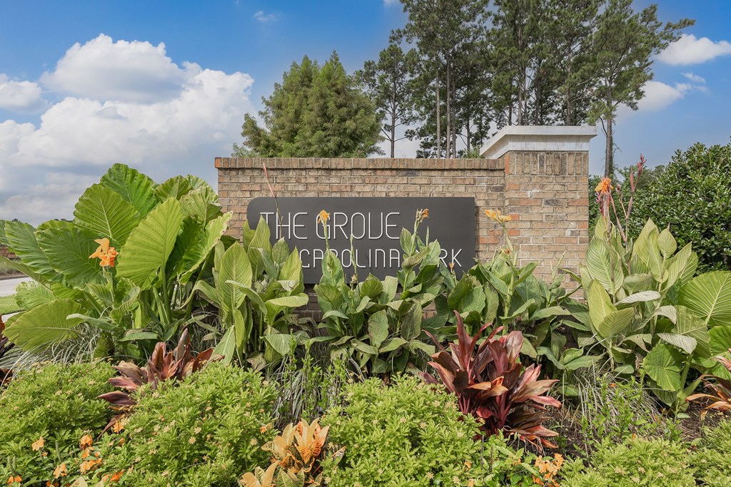 A sign that says "The Orchard" is surrounded by plants.