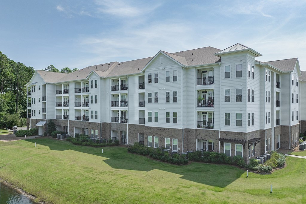 A large white apartment building with a grassy lawn in front.