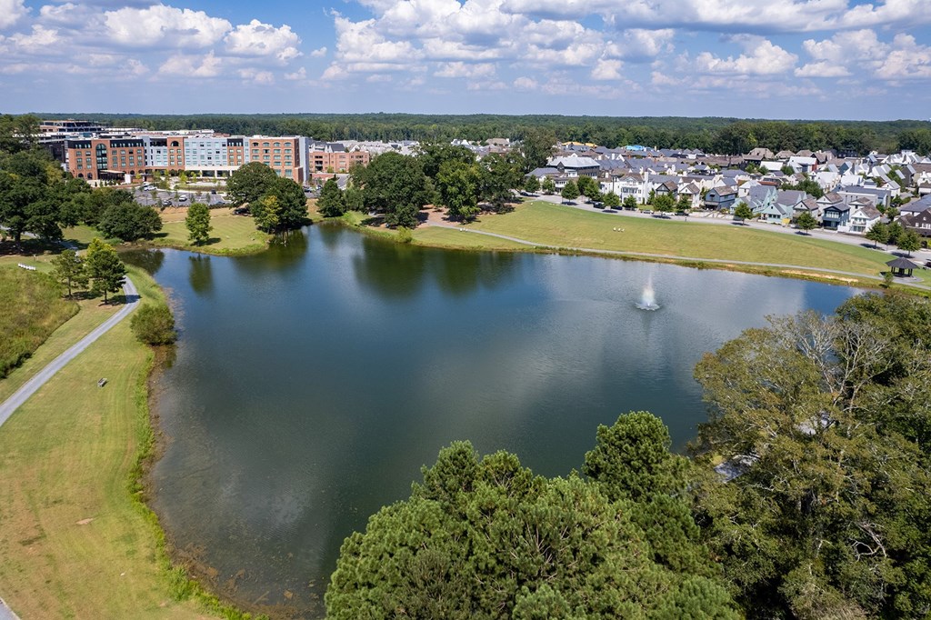 A serene lake surrounded by lush greenery and buildings in the distance.