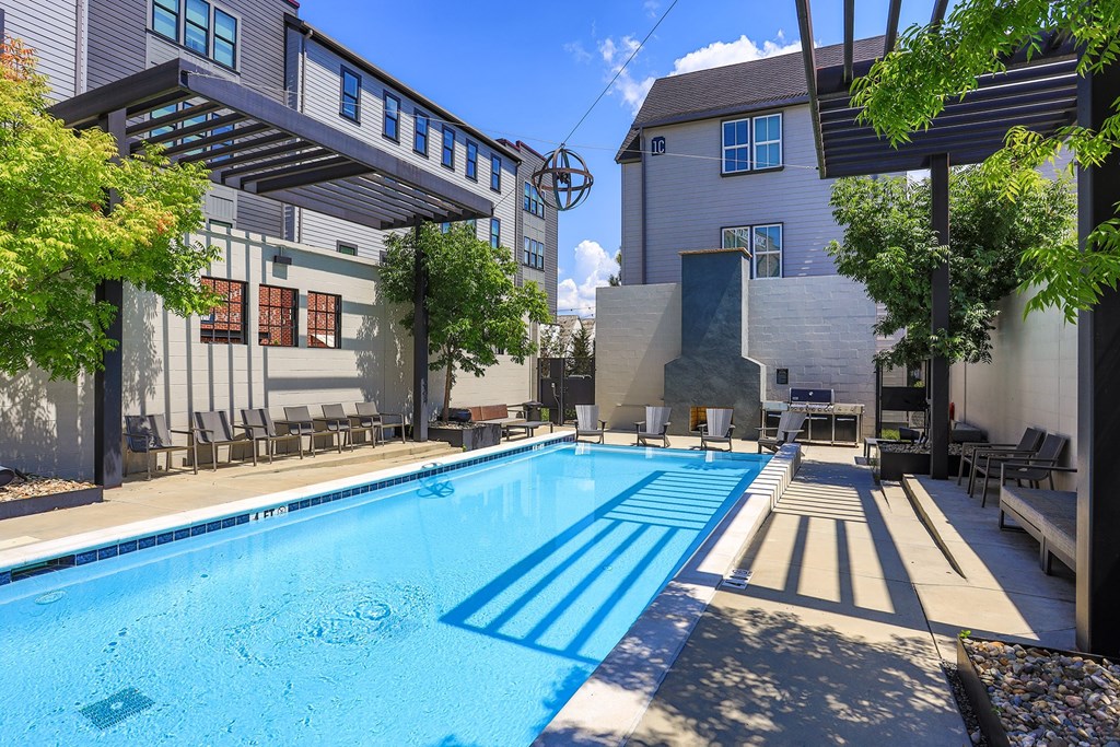 A swimming pool surrounded by a concrete floor and a building in the background.