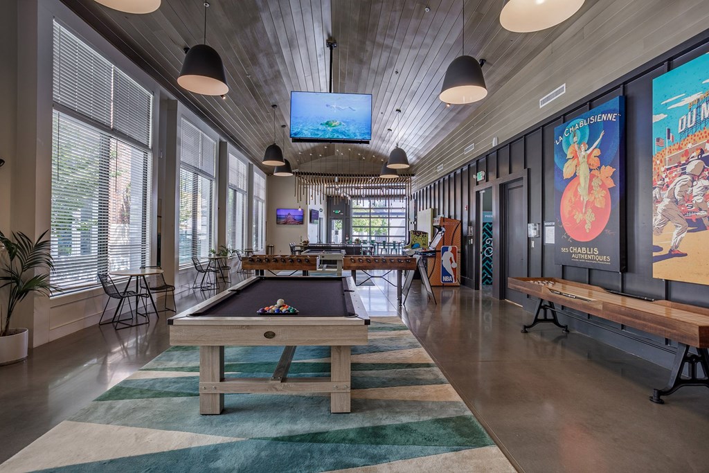 A billiard table is in the middle of a room with a TV mounted on the wall.