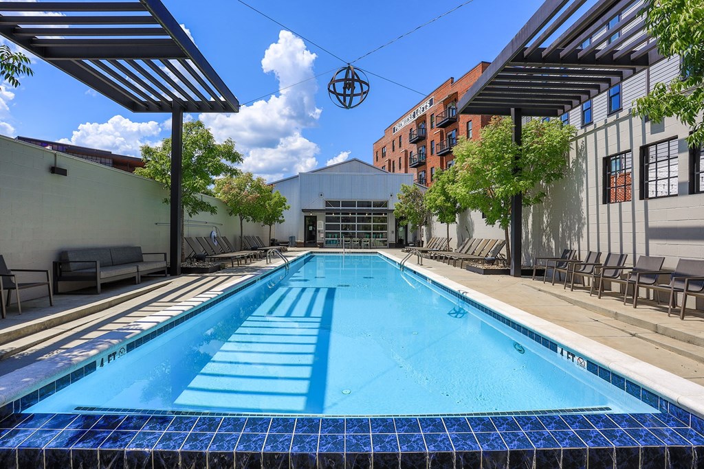 A blue tiled pool surrounded by a metal fence and trees.