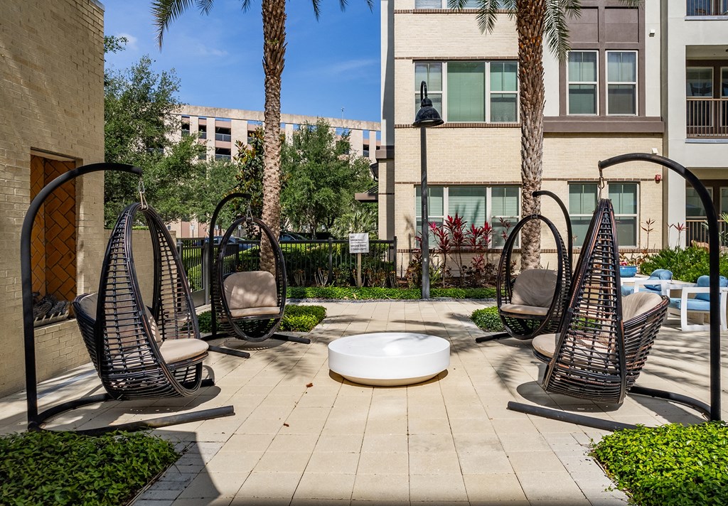 a courtyard with three hammock chairs and a fire pit