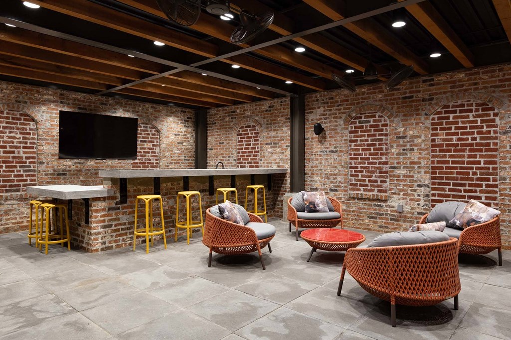 a lobby with chairs and a bar with a brick wall
