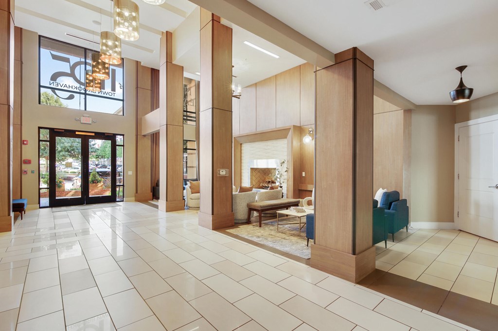 A large, open living room with a white tile floor and a glass door leading to a balcony.