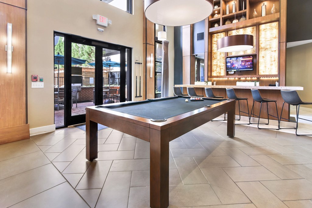 A pool table in a room with a television and a bar.