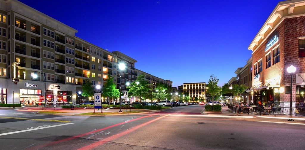 A city street at night with buildings on either side and cars driving down the road.