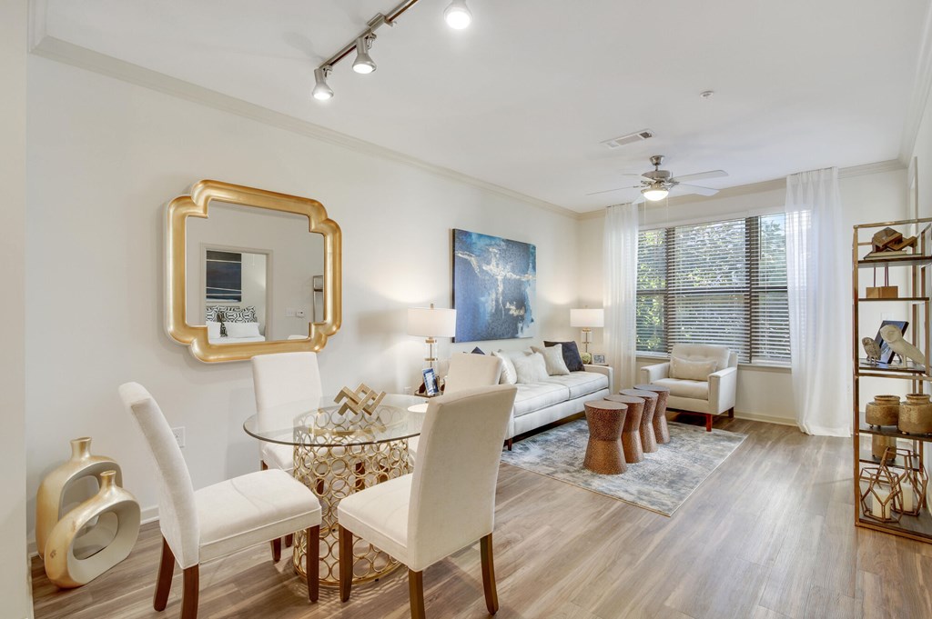 A living room with a glass table and white chairs.