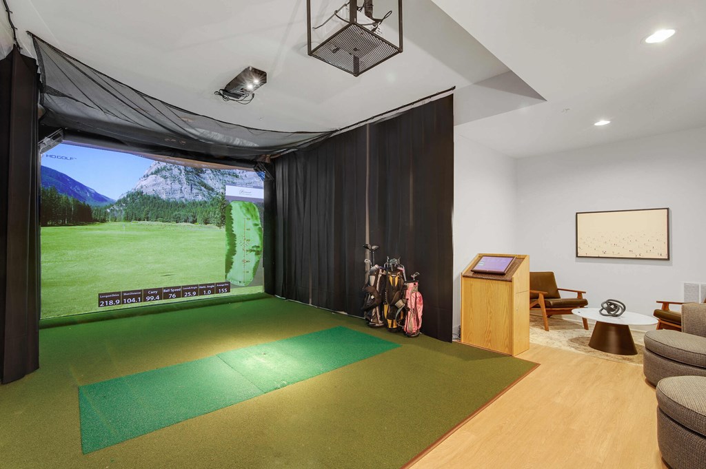 A room with a green mat on the floor and a screen on the wall.